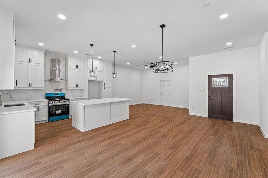 Kitchen with stainless steel electric range, decorative light fixtures, decorative backsplash, white cabinetry, and recessed lighting