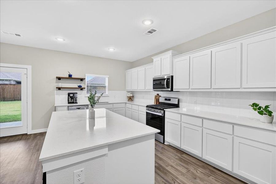 Kitchen featuring stainless steel appliances, white cabinets, light wood-style flooring, backsplash, and recessed lighting