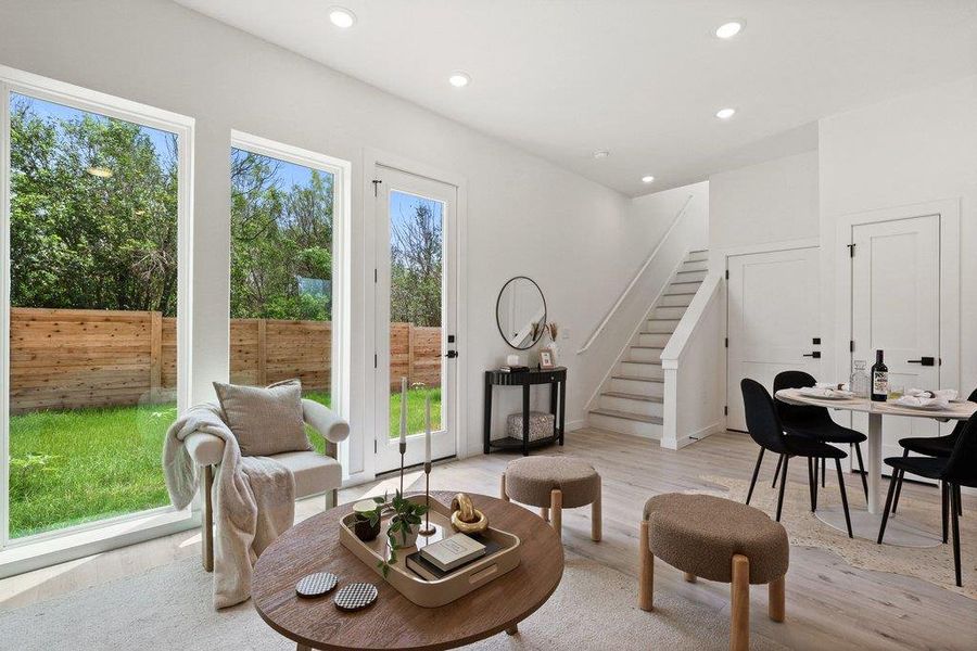Bright living space featuring large windows, a glass-paneled door, and recessed lighting