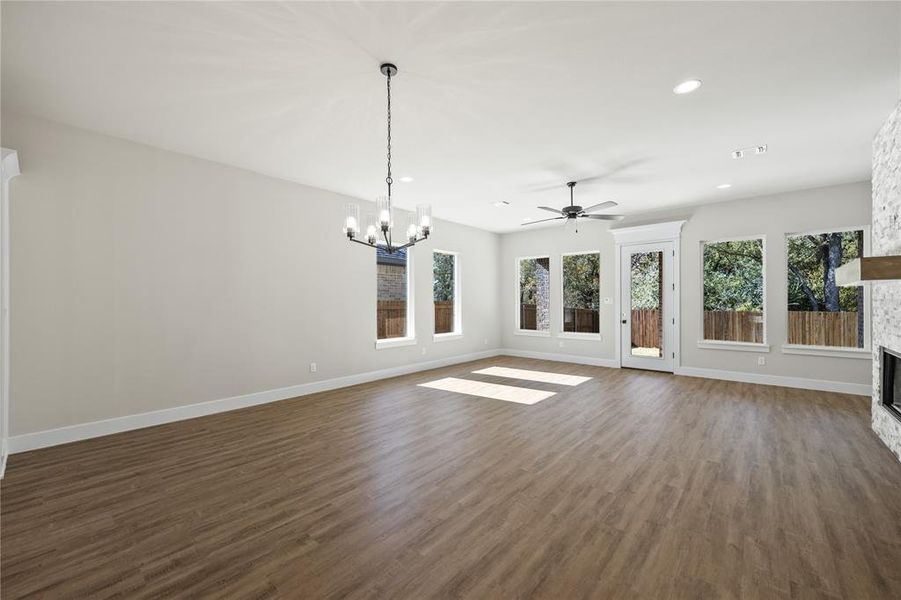 Unfurnished living room with dark wood-type flooring, recessed lighting, plenty of natural light, a ceiling fan, and a stone fireplace
