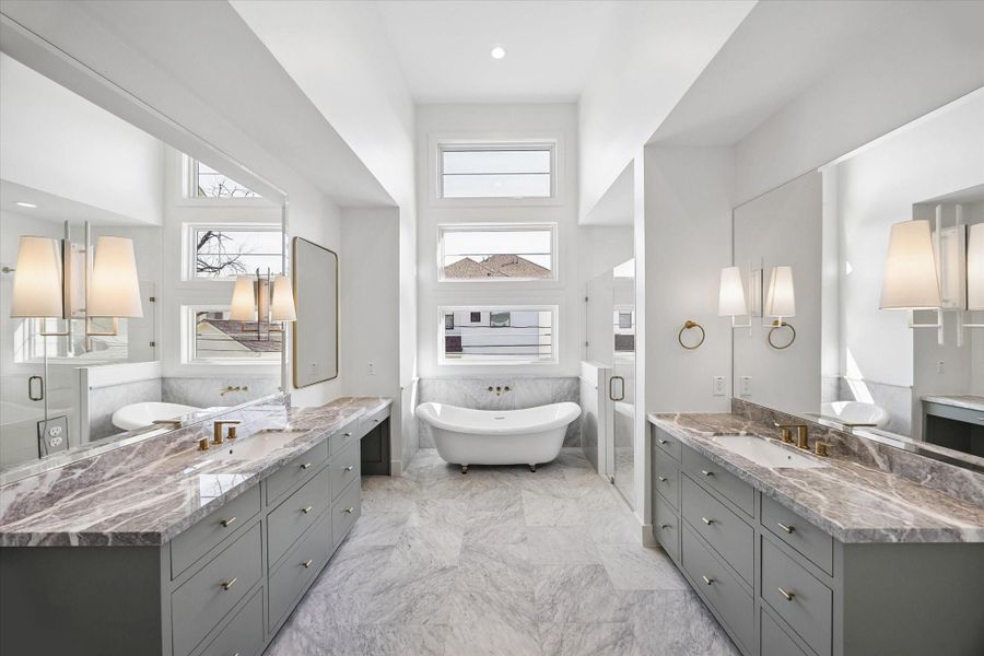 Spa inspired primary bath stuns with dual sage vanities topped in dramatic marble and accented by warm brass fixtures. Freestanding soaking tub framed by stacked picture windows creates a light filled focal point, while a glass enclosed shower completes the retreat experience.**PREVIOUS BUILDER WORK** Spa inspired primary bath stuns with dual sage vanities topped in dramatic marble and accented by warm brass fixtures. Freestanding soaking tub framed by stacked picture windows creates a light filled focal point, while a glass enclosed shower completes the retreat experience.**PREVIOUS BUILDER WORK**