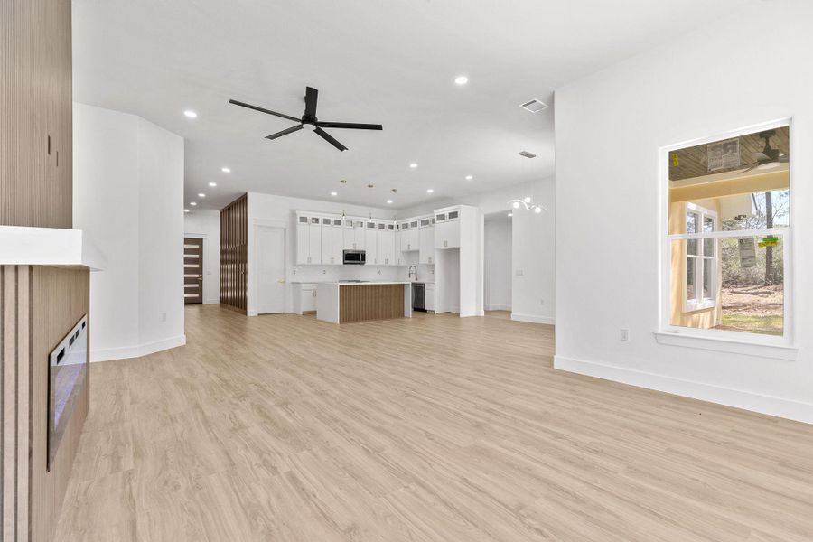 Unfurnished living room with a ceiling fan, light wood-style floors, a fireplace, and recessed lighting