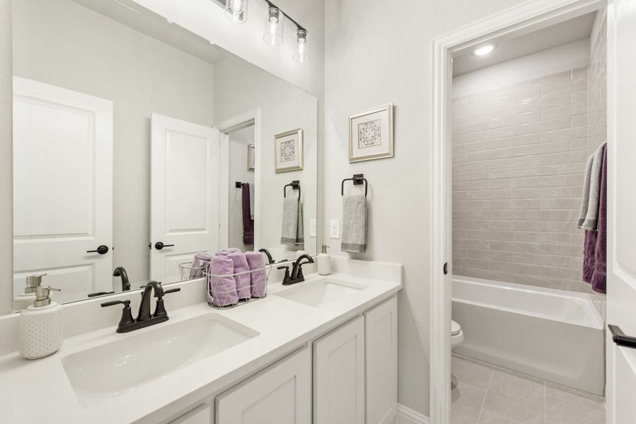 Bathroom with double sink vanity, white cabinets, and tiled tub-shower combo with gray subway tile