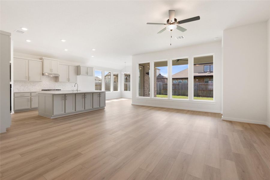 Kitchen featuring open floor plan, a center island with sink, recessed lighting, light wood finished floors, and decorative backsplash