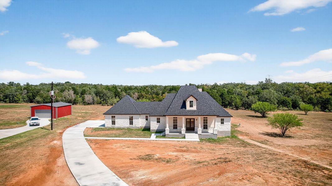 View of front of property featuring a porch, an outbuilding, and stone siding View of front of property featuring a porch, an outbuilding, and stone siding