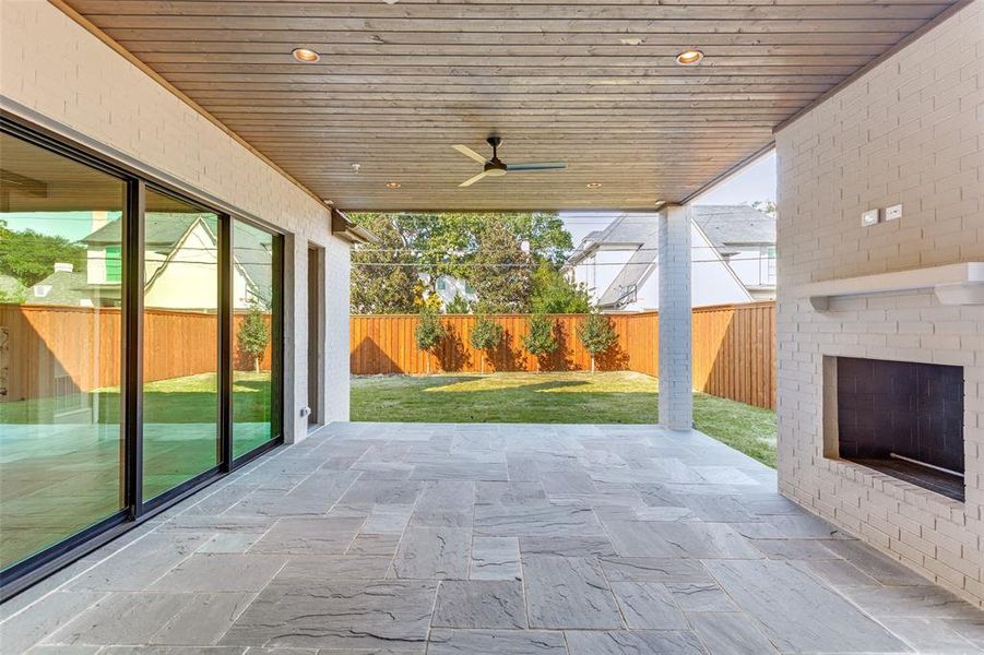 Fenced backyard featuring a patio area, ceiling fan, and an outdoor brick fireplace Fenced backyard featuring a patio area, ceiling fan, and an outdoor brick fireplace