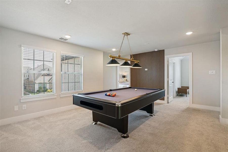 Versatile bonus room featuring light-colored carpet, two windows with blinds, recessed lighting, and a distinctive wood-slat accent wall
