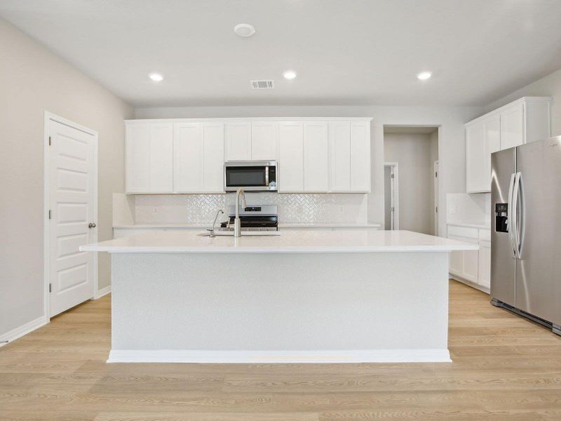 Kitchen with stainless steel appliances, an island with sink, backsplash, white cabinetry, and recessed lighting Kitchen with stainless steel appliances, an island with sink, backsplash, white cabinetry, and recessed lighting