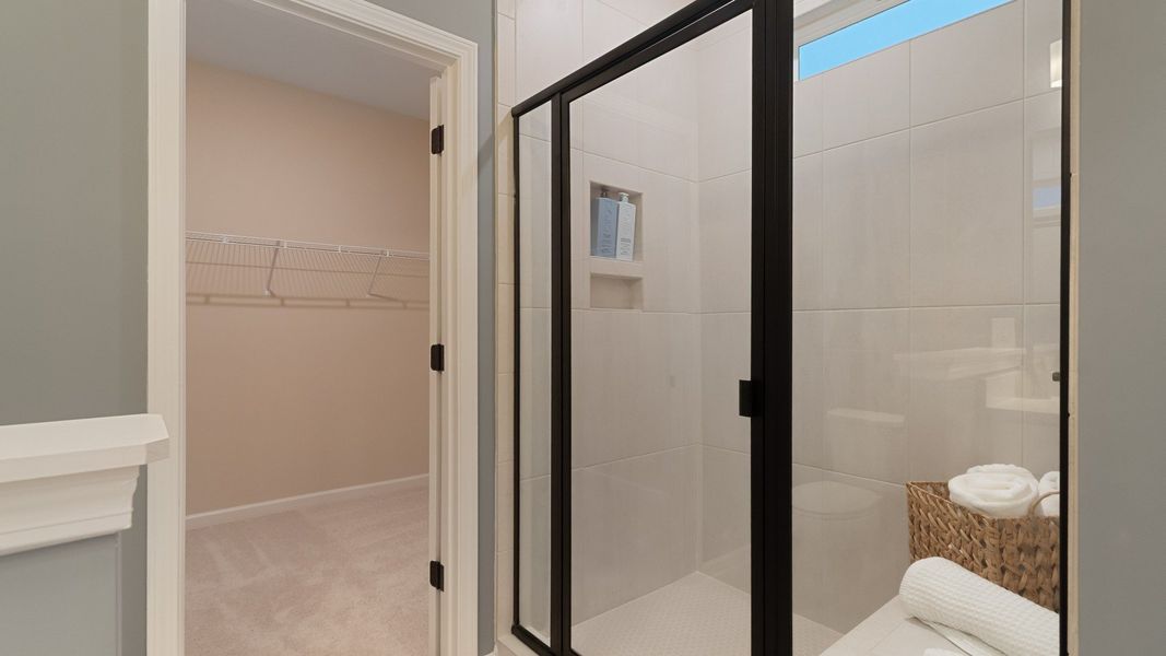 Modern tiled shower with glass door, built-in niche, sleek hardware and built-in bench.