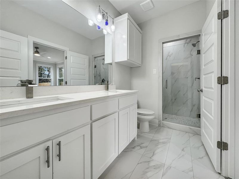 Bathroom with double vanity, a marble finish shower, light marble finish flooring, and a ceiling fan Bathroom with double vanity, a marble finish shower, light marble finish flooring, and a ceiling fan