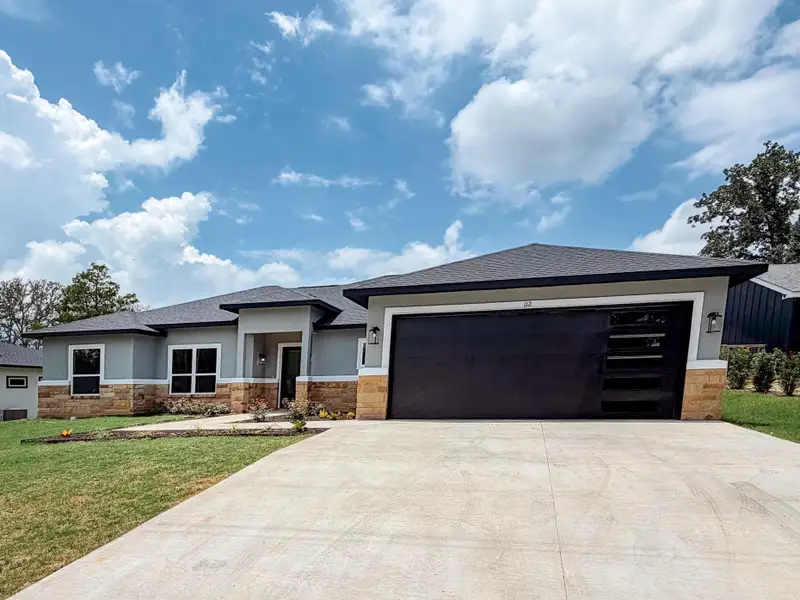 A modern facade with a striking black garage door and stone accents awaits. A modern facade with a striking black garage door and stone accents awaits.