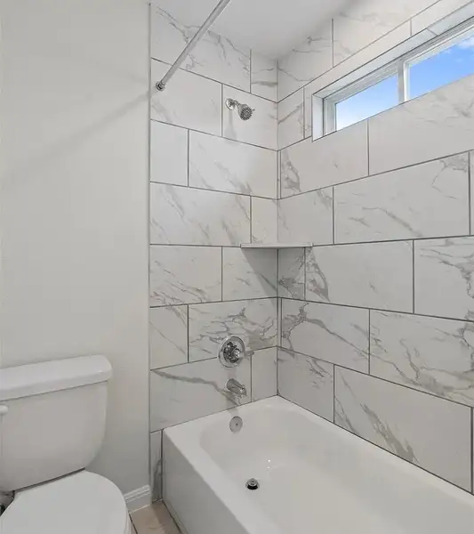 A well-appointed bath features a deep tub and shower with elegant tiled walls.