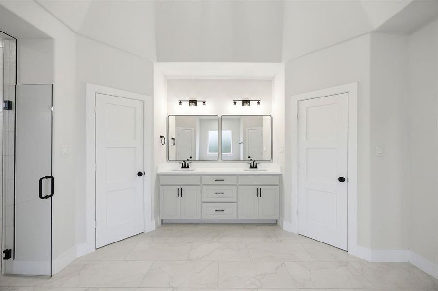 Dual vanity featuring white shaker cabinetry, matte black hardware, and an undermount sink