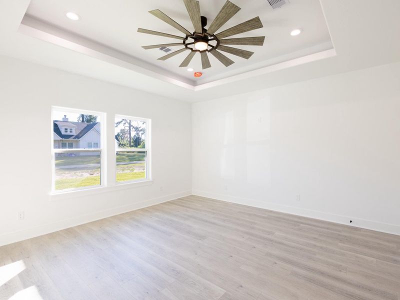 Bright and spacious room with large windows, light wood flooring, and a modern ceiling fan, offering a clean and airy feel.