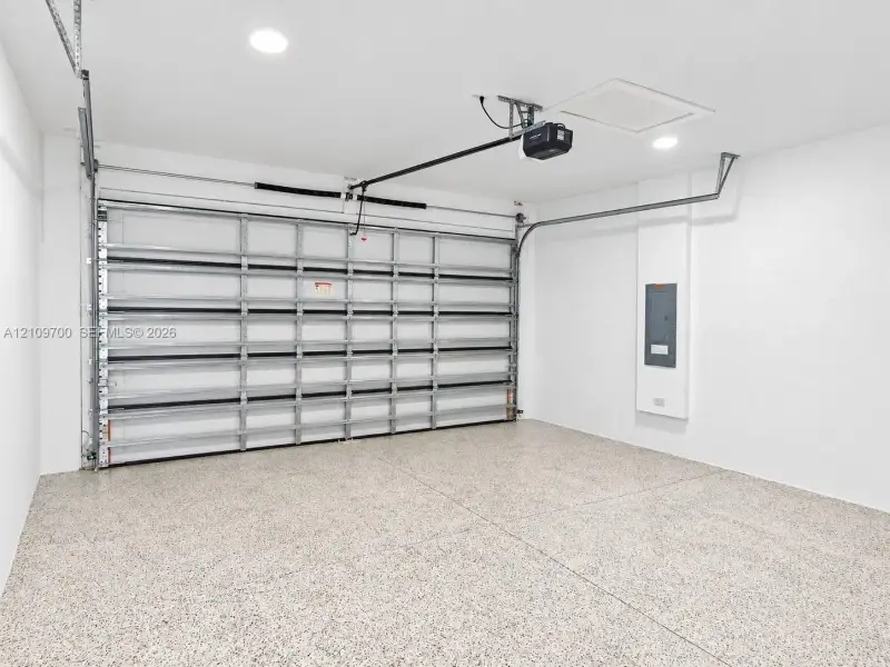 Finished garage space featuring epoxy flooring, recessed lighting, and a metal roll-up door