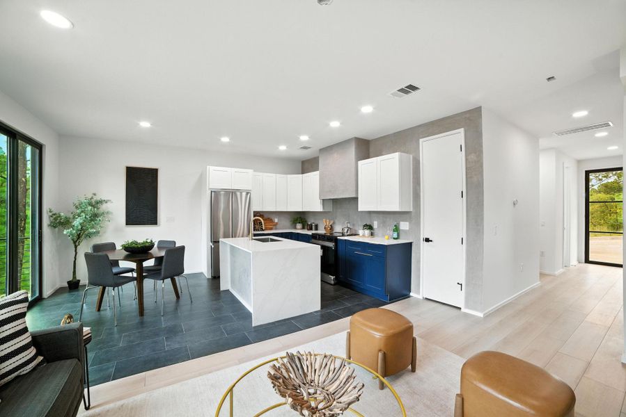 Kitchen featuring light countertops, black range with electric stovetop, recessed lighting, a kitchen island with sink, and freestanding refrigerator Kitchen featuring light countertops, black range with electric stovetop, recessed lighting, a kitchen island with sink, and freestanding refrigerator