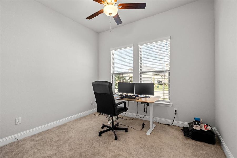 Carpeted home office featuring ceiling fan