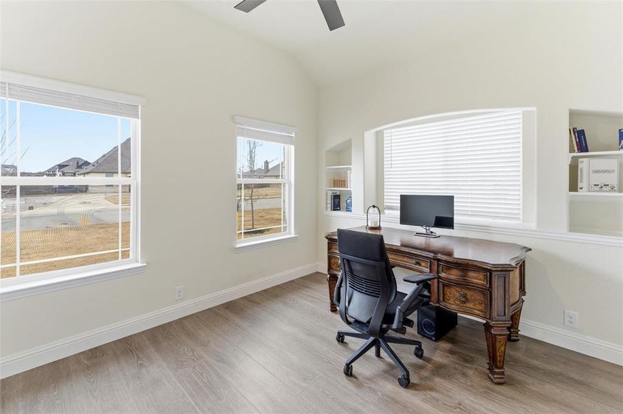 Office featuring a ceiling fan, built in shelves, light wood-style floors, and vaulted ceiling