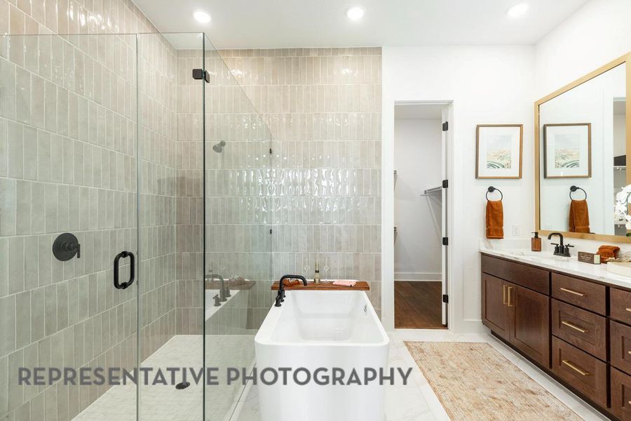 Full bath with a stall shower, a freestanding tub, vanity, a walk in closet, and recessed lighting