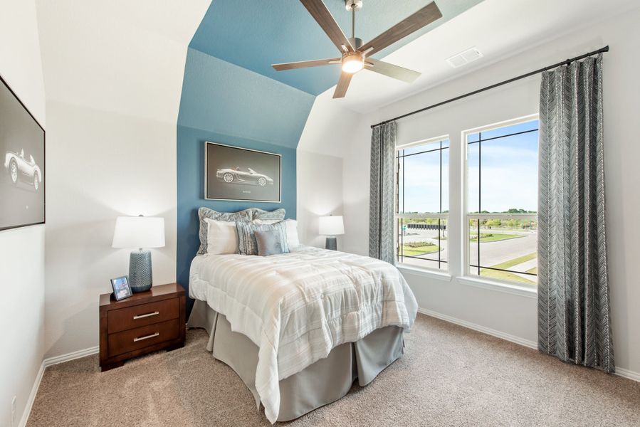 Bedroom with blue arched accent wall, ceiling fan, carpet flooring, and large windows with neighborhood view