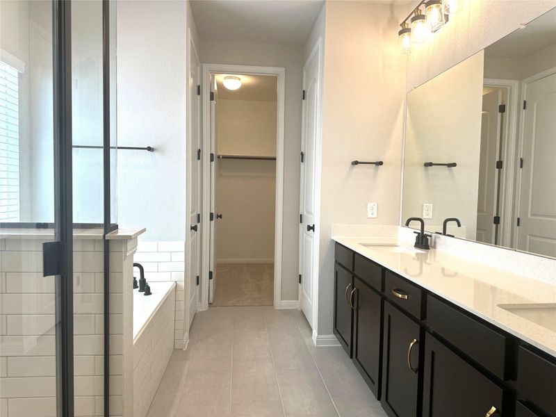 Primary bathroom featuring plenty of natural light, tile flooring, a bath, and a spacious closet Primary bathroom featuring plenty of natural light, tile flooring, a bath, and a spacious closet