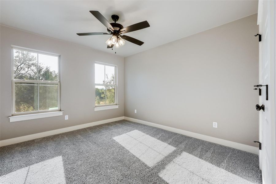 Carpeted empty room with baseboards and a ceiling fan Carpeted empty room with baseboards and a ceiling fan