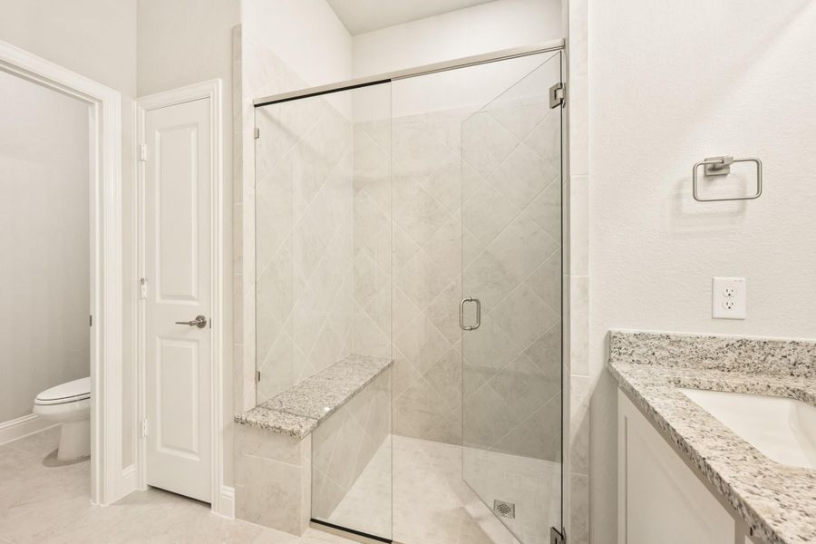Bathroom with glass-enclosed walk-in shower, diagonal tile walls, granite bench seat, and granite vanity countertop Bathroom with glass-enclosed walk-in shower, diagonal tile walls, granite bench seat, and granite vanity countertop