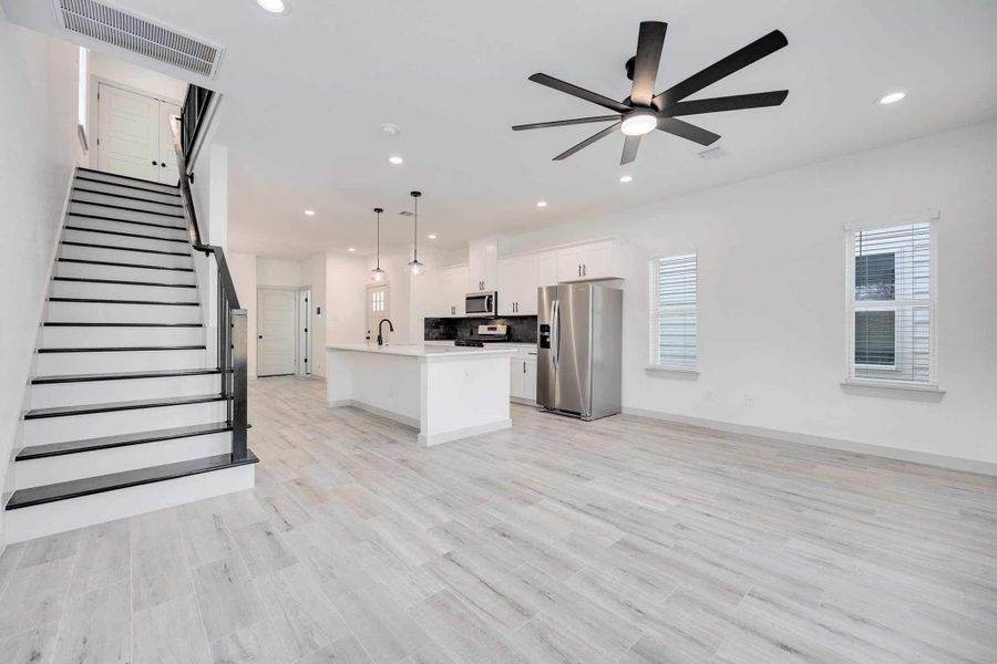 Expansive first floor showcasing the open layout with a modern staircase featuring black railing that adds architectural interest.