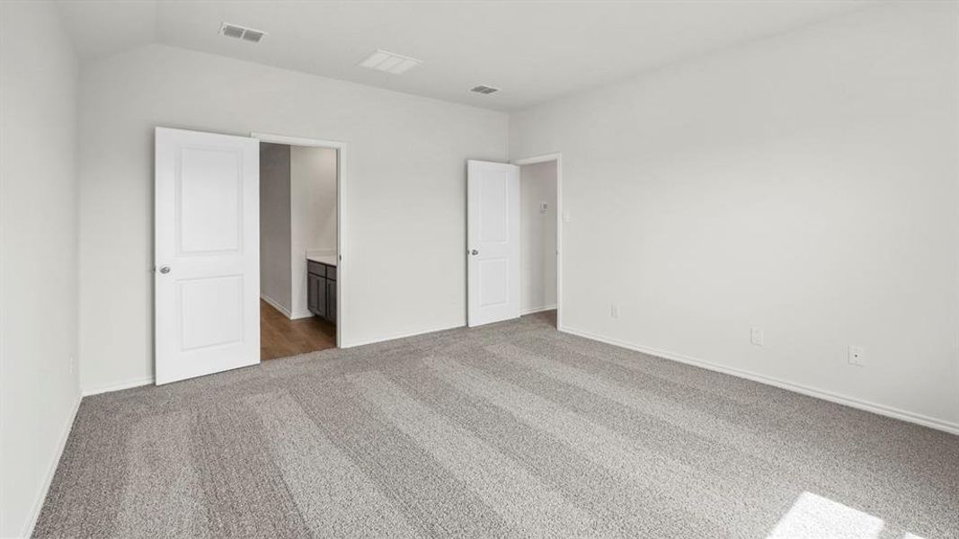 Spacious room featuring light gray carpeting, white walls, and a white ceiling with vents