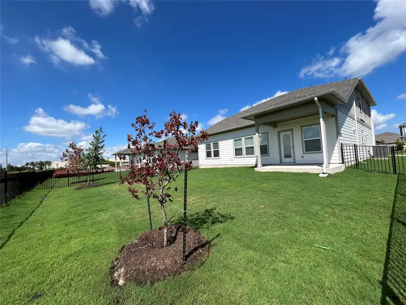 Rear view of property with a fenced backyard, a shingled roof, and a patio area