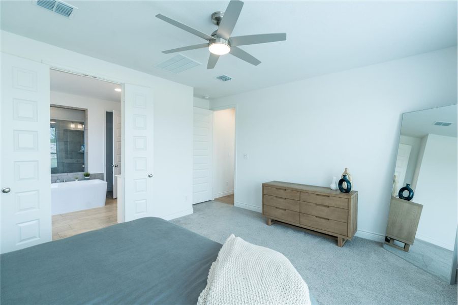 Bedroom with a ceiling fan and light colored carpet