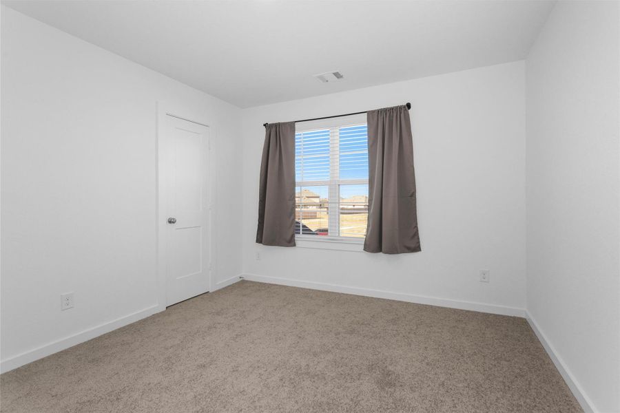 This upstairs secondary bedroom has never been used and features natural light, neutral finishes, and plush carpeting—creating a fresh, move-in ready space for guests, family, or a home office.