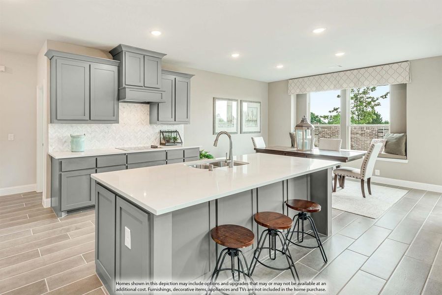 Kitchen with gray cabinets, large island with sink, bar stools, and open dining area with window seating.