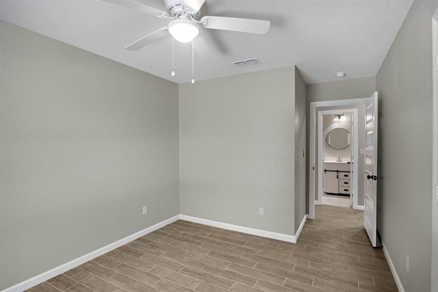 Unfurnished bedroom with wood tiled floors and a ceiling fan Unfurnished bedroom with wood tiled floors and a ceiling fan