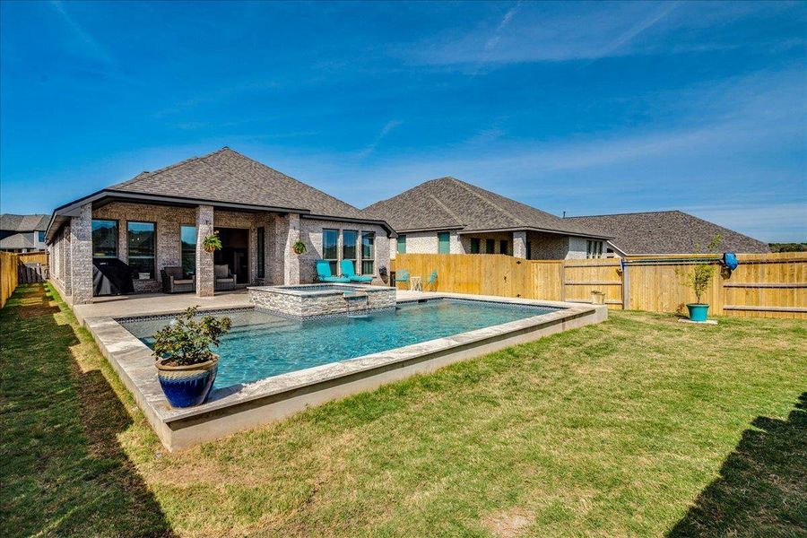 Relaxing pool / spa with a fenced backyard and a patio