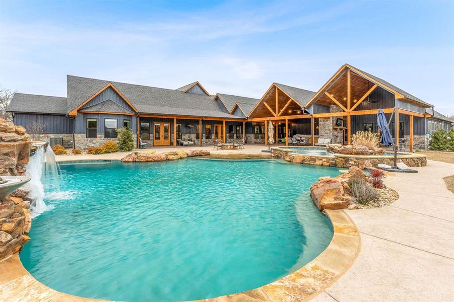 View of swimming pool with a patio area, a pool with connected hot tub, and french doors