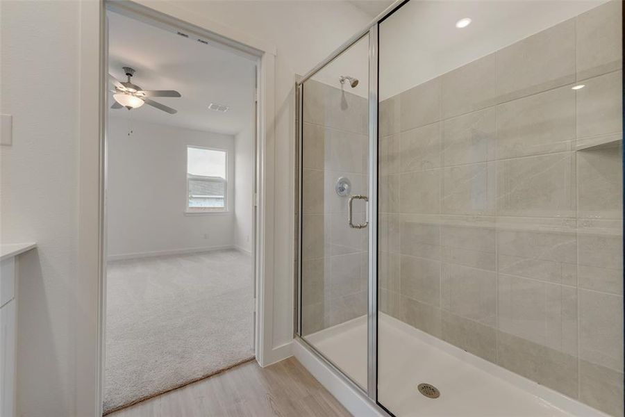 Bathroom with an enclosed shower, ceiling fan, and hardwood / wood-style floors