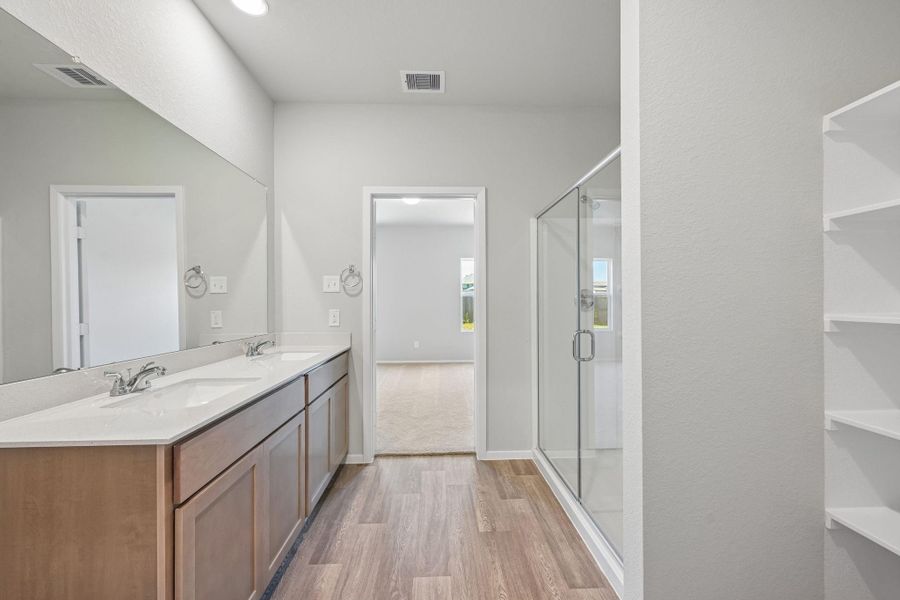 Dual vanities with generous countertop space and abundant storage make daily routines effortless, while thoughtfully placed lighting ensures a warm, inviting glow throughout the space.