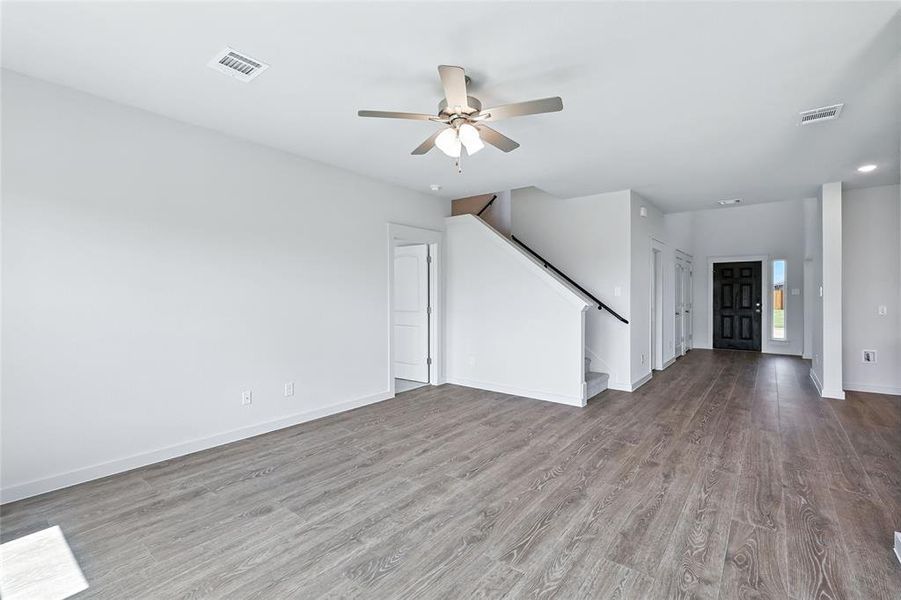 Unfurnished living room featuring wood finished floors, stairs, and a ceiling fan Unfurnished living room featuring wood finished floors, stairs, and a ceiling fan
