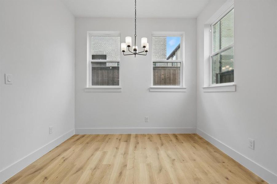 Unfurnished dining area with a chandelier, wood finished floors, and baseboards