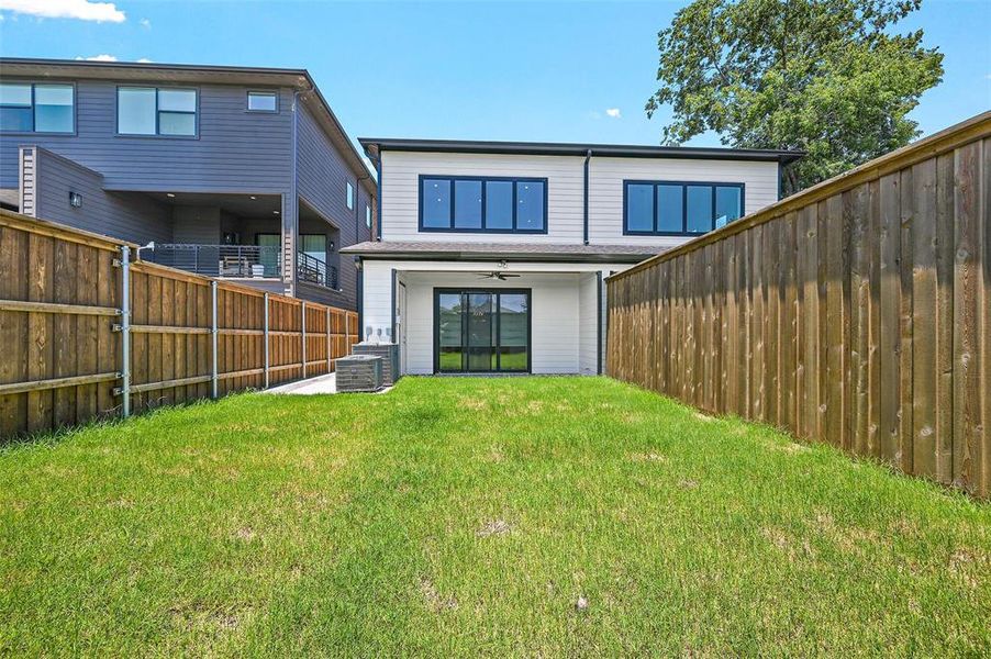 Back of house with a yard and ceiling fan