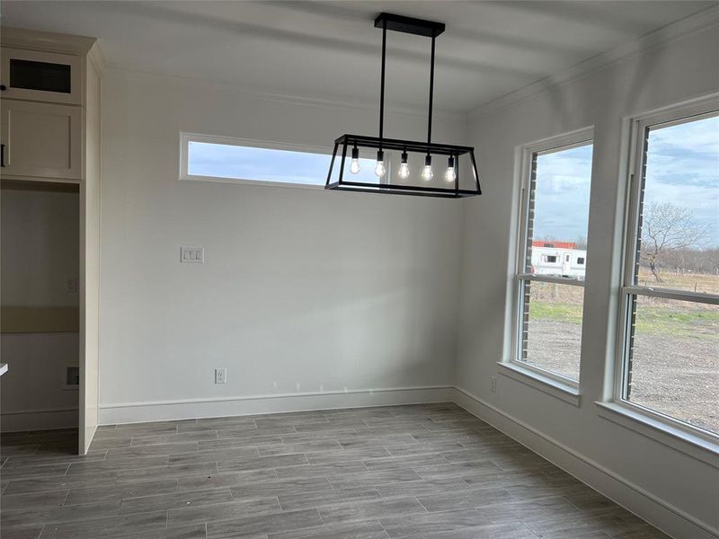 Unfurnished dining area with wood finish floors, ornamental molding, and a chandelier