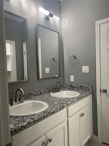 Bathroom with double vanity and a textured wall. Bathroom with double vanity and a textured wall.