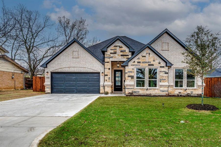 View of front of property featuring a garage and a front lawn