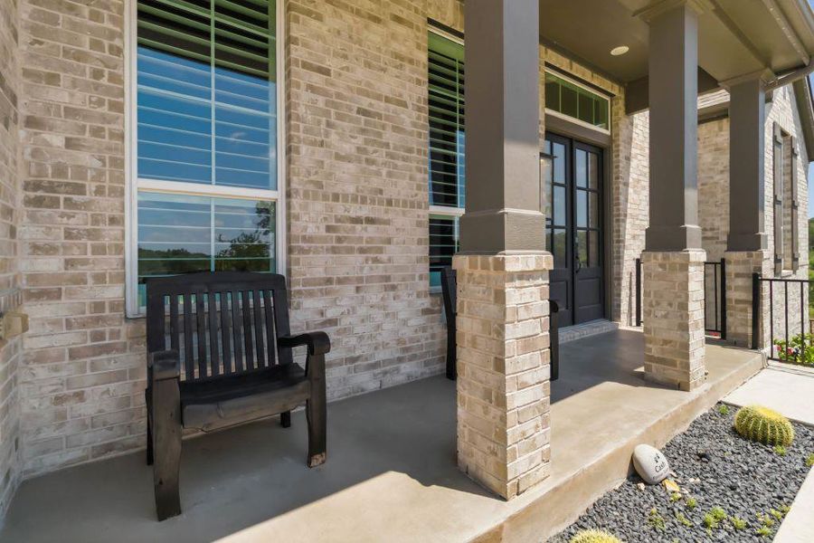 A welcoming front porch with brick pillars and double entry doors offers a charming entrance.