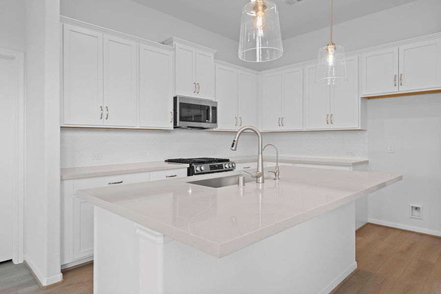 This light and bright kitchen features a large quartz island, white cabinets, a large sink overlooking your family room, recessed lighting, and beautiful backsplash. This light and bright kitchen features a large quartz island, white cabinets, a large sink overlooking your family room, recessed lighting, and beautiful backsplash.