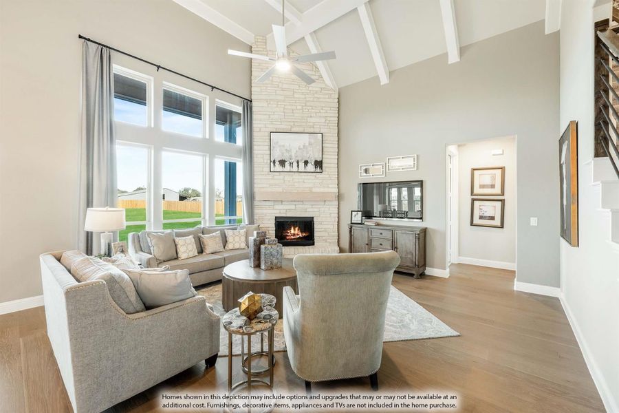Living room with vaulted beamed ceiling, stone fireplace, hardwood floors, and large windows