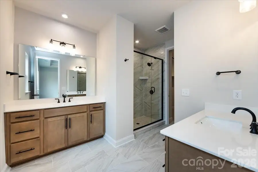 Dual vanity primary bathroom with warm brown cabinets Dual vanity primary bathroom with warm brown cabinets