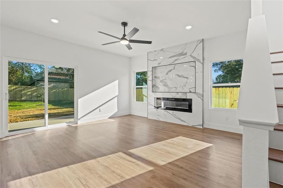 Unfurnished living room featuring a ceiling fan, wood finished floors, a premium fireplace, recessed lighting, and stairway