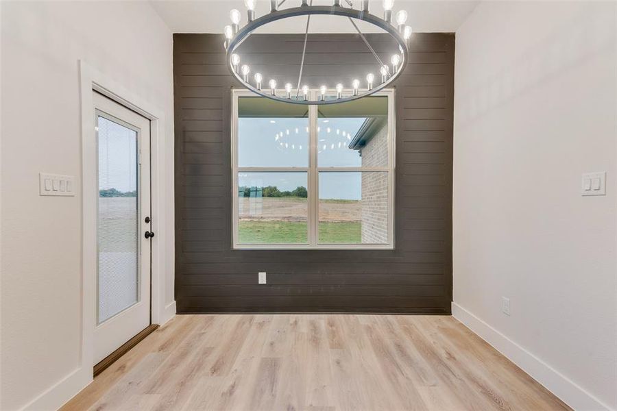 Unfurnished dining area with wooden walls, light wood-style flooring, and plenty of natural light Unfurnished dining area with wooden walls, light wood-style flooring, and plenty of natural light
